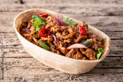 Mexican barquita taco with beef, chilli, tomato, onion and spices on wooden table	