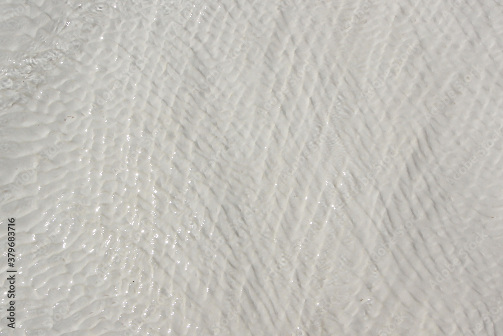 background of white travertine surface covered with flowing clear water with waves