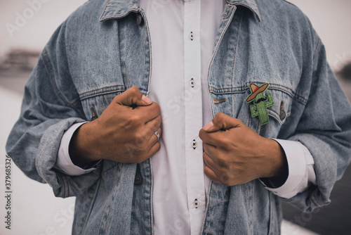 pair of young people a man and a woman dressed in white wedding clothes denim blue jackets.Mexican people on a snowy white background.boutonnieres green small fabric cactus badges.Dark tanned hands
