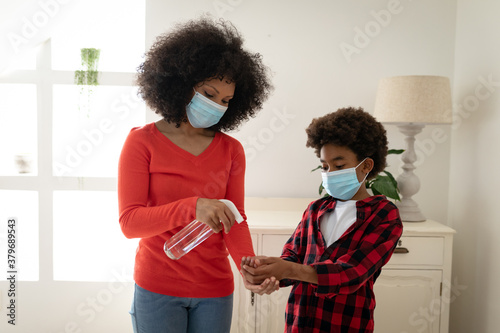 Mother sanitizing hands of her son at home