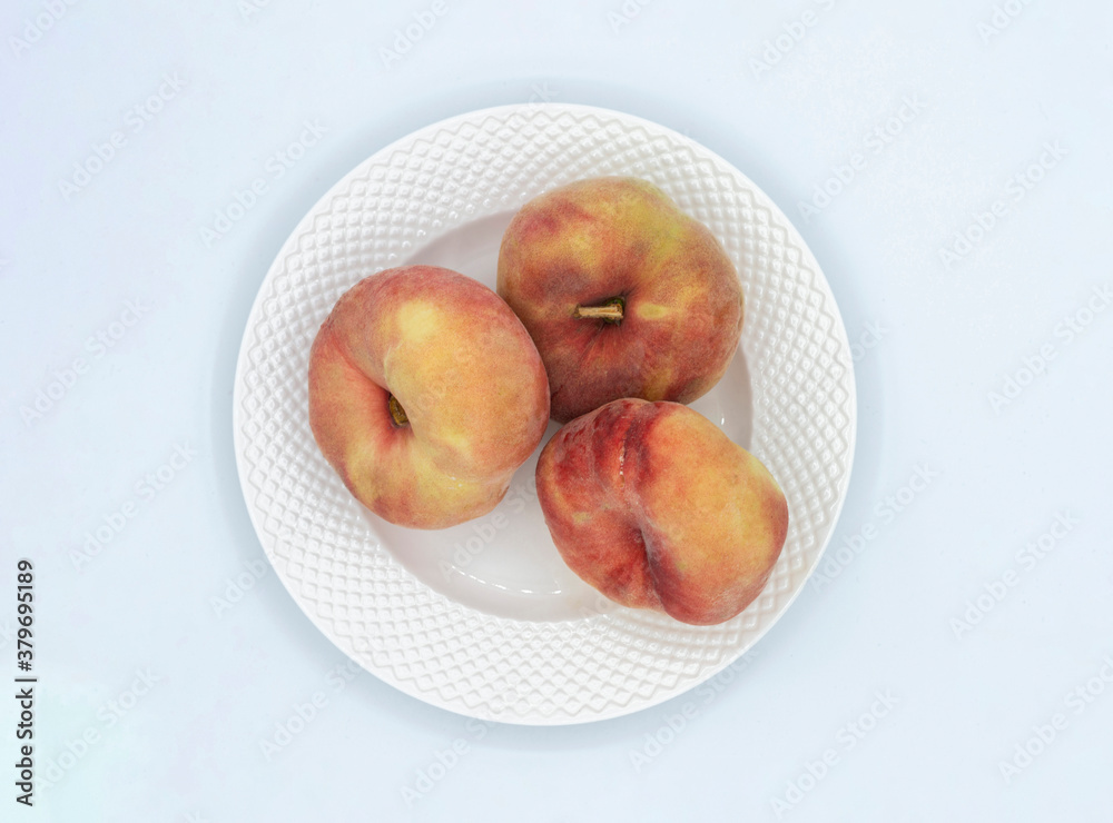 VIEW OF THREE FRUITS CALLED PARAGUAYAS FROM ABOVE ON A WHITE PLATE VIEW OF THREE FRUITS CALLED PARAGUAYAS FROM ABOVE ON A WHITE PLATE