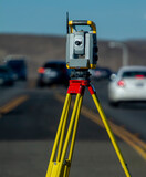Land survey equipment set up on road with road becoming a hill in the background with traffic