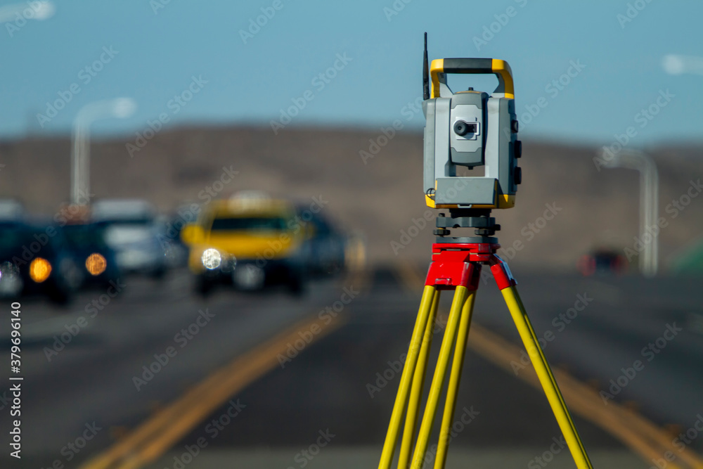 Land survey equipment set up on road with road becoming a hill in the background with traffic