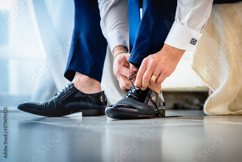 Man puts on elegant black shoes.