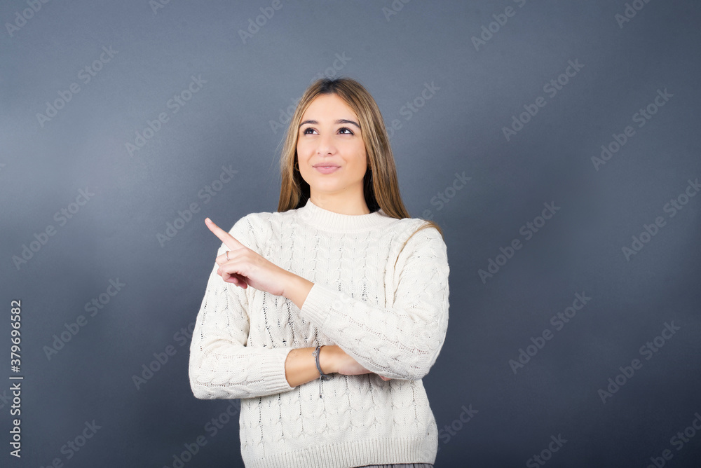 Beautiful young blonde woman wearing white sweater standing against gray background, Beautiful young blonde woman wearing white sweater standing against gray background,