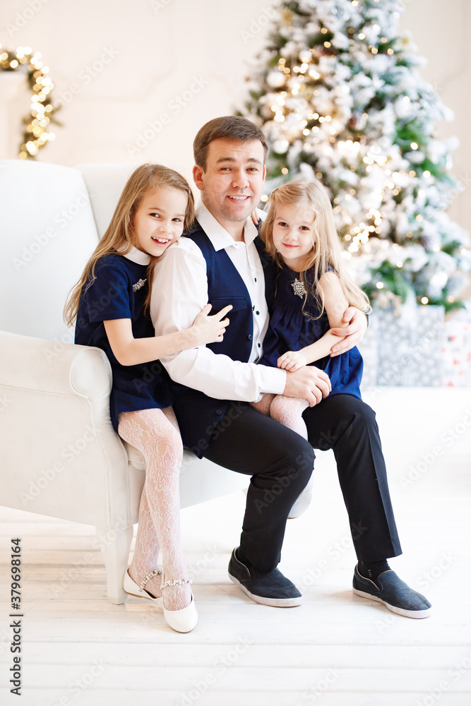 father and daughter on a chair on the background of a Christmas tree. happy fatherhood. new year vacations. father and daughter on a chair on the background of a Christmas tree. happy fatherhood. new year vacations.