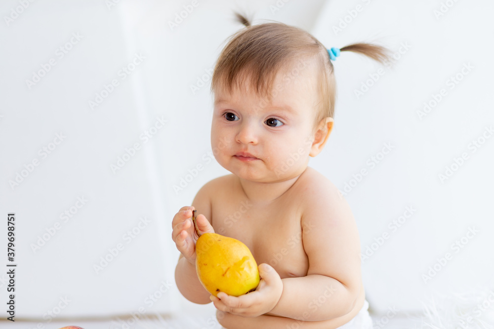 portrait of a cute little girl six months old with a pear in her hands on a white background portrait of a cute little girl six months old with a pear in her hands on a white background