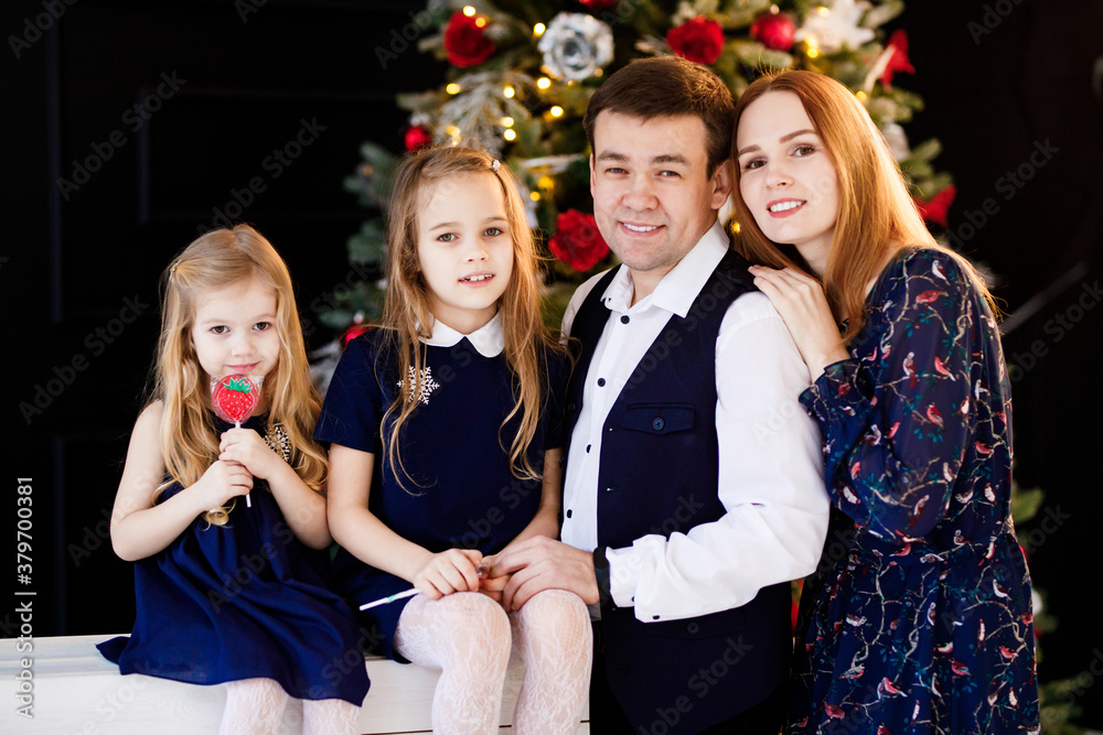 father, mother and daughters in new year decor. family photo shoot for Christmas. annual traditions of celebration. happy and fun holidays.