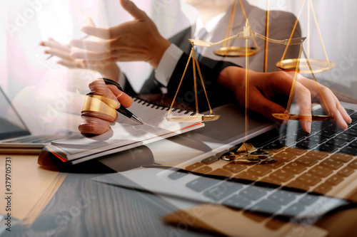 Justice and law concept.Male judge in a courtroom with the gavel, working with, computer and docking keyboard, eyeglasses, on table in morning light