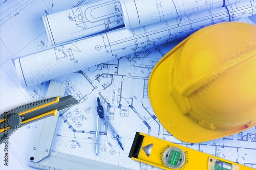 Paper blueprints, a yellow hardhat and tools