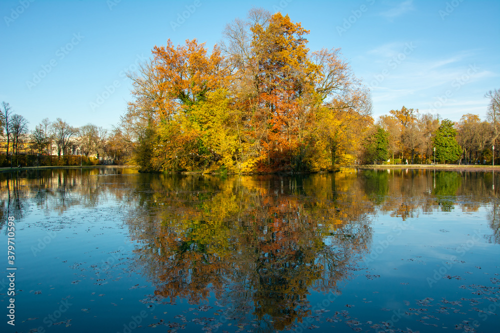 Beautiful autumn trees reflecting on a steel lake in Parma, Italy
