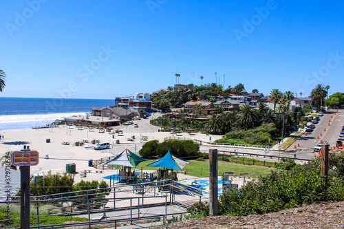 gorgeous shot of the blue ocean water, lush green palm trees and beach houses with people walking along the beach at Moonlight State Beach in Encinitas California USA photo