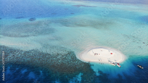 A beautiful drone photography of Maldives. The clear ocean with different tons of blue, the coral reef and the green palm trees makes that place special destination for tourism.