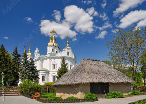 Quadro em tela Traditional Ukrainian architecture - house with adobe walls and thatched roof and church with golden cupolas