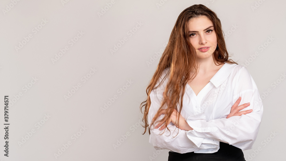 Ambitious woman portrait. Commercial background. Confident female CEO in white shirt standing with crossed arms isolated on light empty space wall. Professional success. Leader lifestyle. Ambitious woman portrait. Commercial background. Confident female CEO in white shirt standing with crossed arms isolated on light empty space wall. Professional success. Leader lifestyle.
