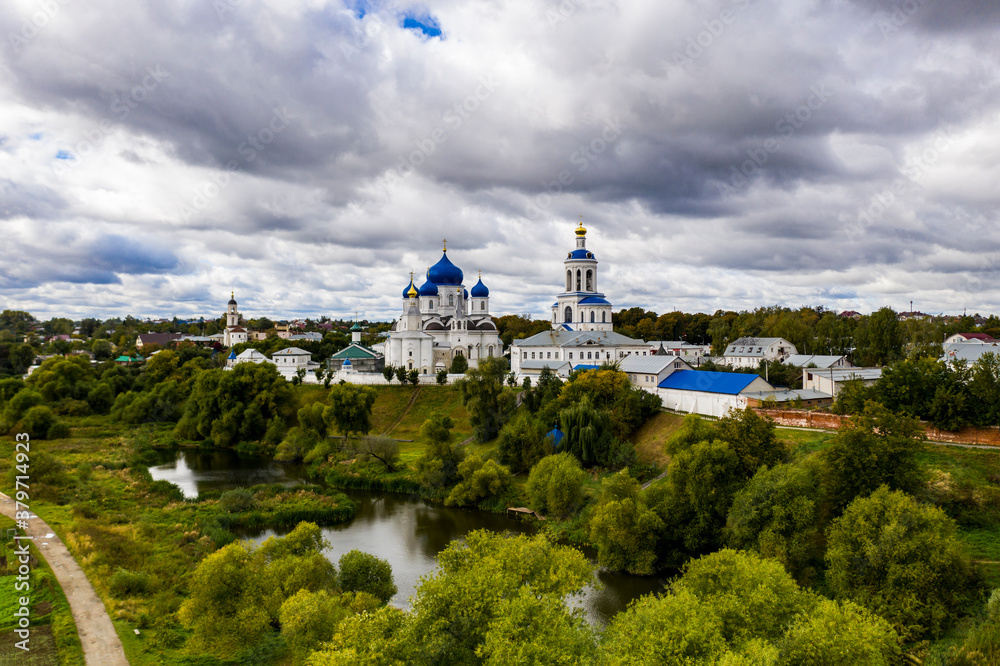 a panoramic view of the old monastery of white stone with blue domes against the background of blue clouds filmed from a drone