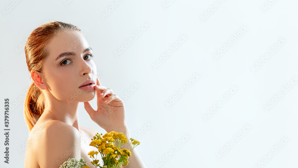 Fototapeta premium Organic cosmetology. Beauty care. Portrait of sensual woman with perfect face skin nude makeup bare shoulders wild flowers isolated on white copy space background. Alternative medicine. Eco detox