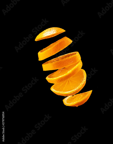 Falling orange and orange slices. Isolated on a black.