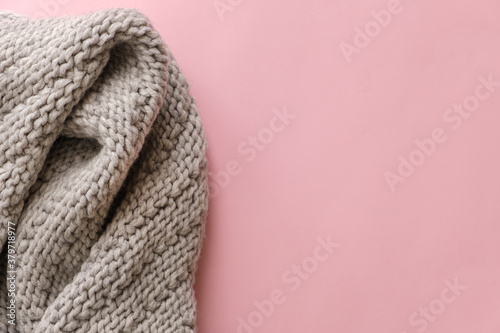 Gray knitted scarf on pink background with copy space