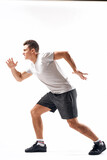 Athletic man on a light background in full growth and jogging charging shorts sneakers t-shirt