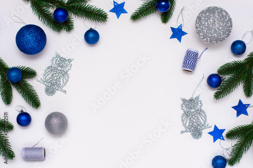 Christmas flatlay with fir branches, blue and silver  decorations on white background. Christmas composition, top view, copy space.