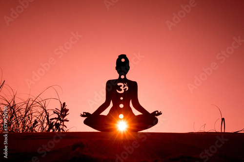 Silhouette of a person doing yoga with the root chakra symbol photo