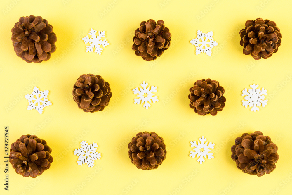 Obraz premium Top view of New Year ornament made of white snowflakes and pine cones on colorful background. Winter holiday concept with empty space for your design