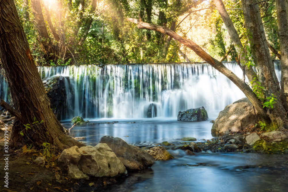 Fototapeta premium Natural waterfall called “Cascada del Hervidero” in Madrid, in the forest, with sunlight between vegetation and rocks. 
