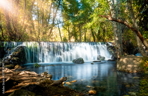 Natural waterfall called “Cascada del Hervidero” in Madrid, in the forest, with sunlight between vegetation and rocks. 