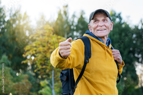 old traveler man with smile on face wearing cap calling people to adventure in mountains forest background