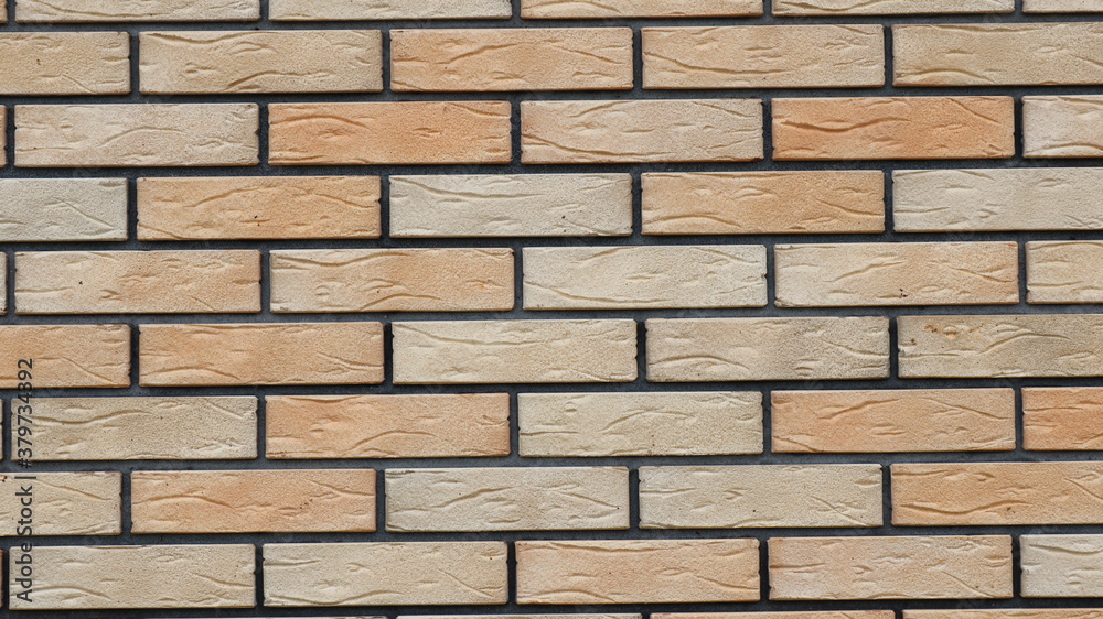 a fragment of flat new brickwork in the structure of a wall or fence with blocks of different light shades of brown and contrasting dark cement joints a fragment of flat new brickwork in the structure of a wall or fence with blocks of different light shades of brown and contrasting dark cement joints