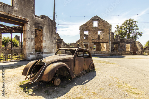 Old car in a ruined street - Oradour sur Glane, French village located in the Haute-Vienne department - martyred village victim of a massacre during the Second World War - historical ruins photo
