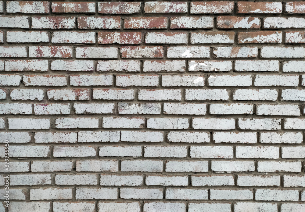 A clean wall of old brick painted with gray paint, which has peeled off in places.