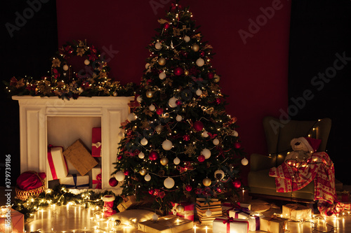 Christmas tree with gifts of garland lights for the new year in the interior of the night room as a red background