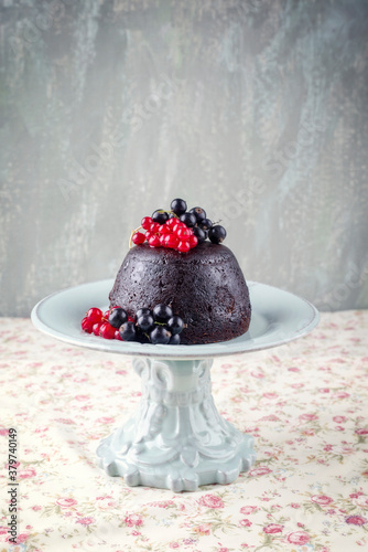 Traditional Australian plum pudding with fresh forest berries offered as close-up on a design dessert plate on a table with copy space. photo