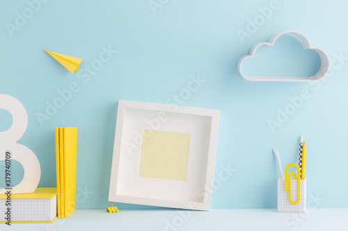 Creative young student workspace, with white empty frame,yellow supplies and cloud on the wall. photo