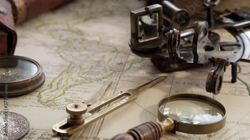 Dolly shot of vintage sextant and other instruments on ancient world map of the 17th century