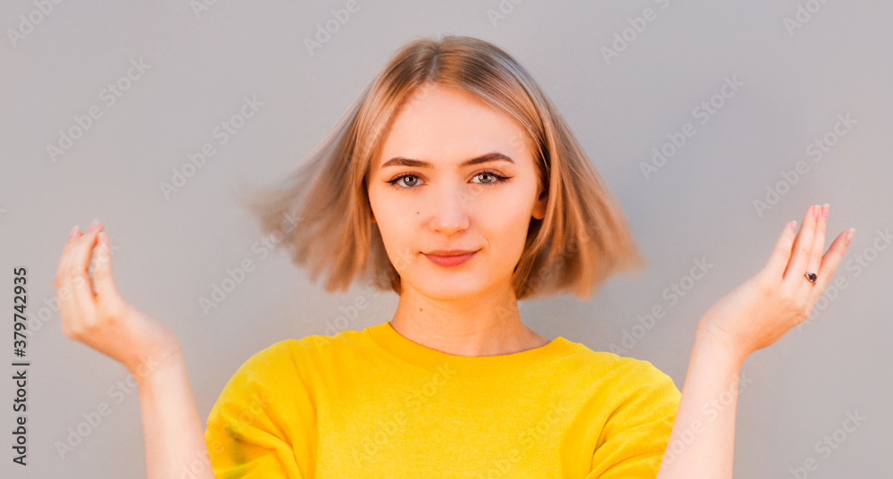 Fototapeta premium Awesome attractive joyful happy sexy female model is shaking head with blond hair in studio isolated on gray background