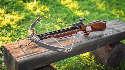 Loaded crossbow on a wooden bench. Selective focus.