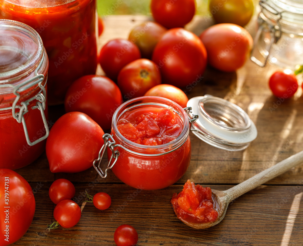 Homemade tomato preserves and fresh tomatoes on a wooden table close up view Homemade tomato preserves and fresh tomatoes on a wooden table close up view