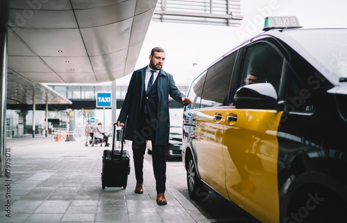 Handsome male passenger in formal outfit sitting in yellow cab getting to business meeting during travel trip, Caucasian man lawyer with baggage suitcase ordering taxi transport at airport exterior
