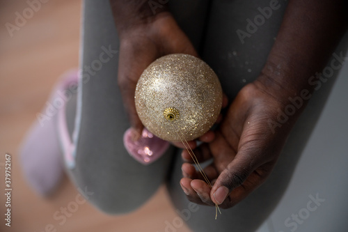 Girl holding shiny golden holiday bauble in her hands