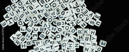 Randomly scattered white cubes with letters isolated on a black background.
