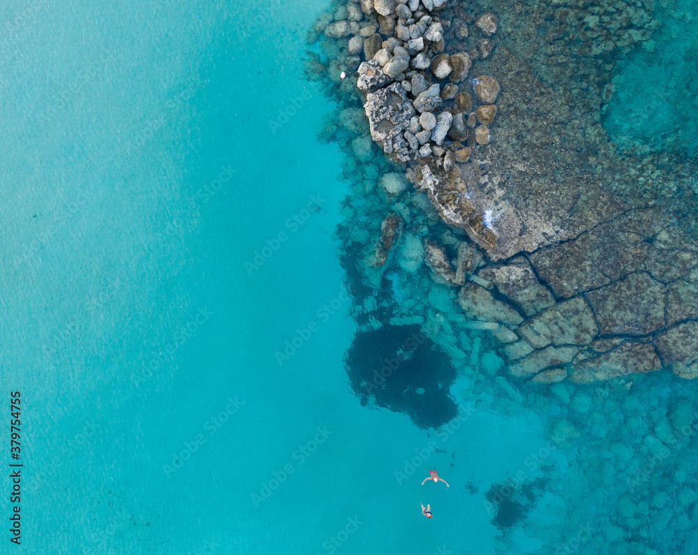 An aerial view of the beautiful Mediterranean Sea, where you can see the cracked rocky textured underwater corals and the clean turquoise water of Protaras, Cyprus,	