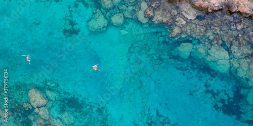An aerial view of the beautiful Mediterranean Sea and a swimmer, where you can see the cracked rocky textured underwater corals and the clean turquoise water of Protaras, Cyprus,