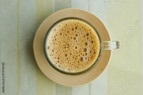 Selective focus of "kopi tarik" or milk coffee foam on table. One of famous Malaysia drink to stay awake and fit everyday