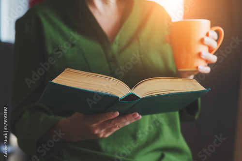 young woman reading book and drinking coffee