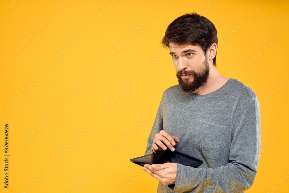 Emotional man with tablet in hands technology internet device lifestyle yellow background