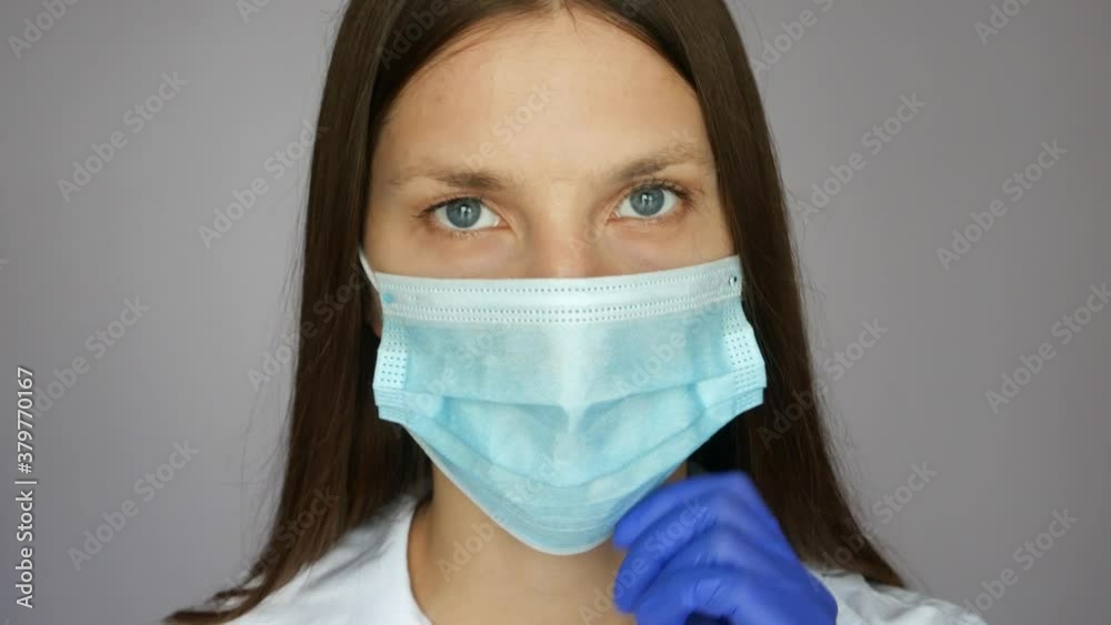 A portrait of a very beautiful nurse looking at the camera and adjusting her protective mask close up A portrait of a very beautiful nurse looking at the camera and adjusting her protective mask close up