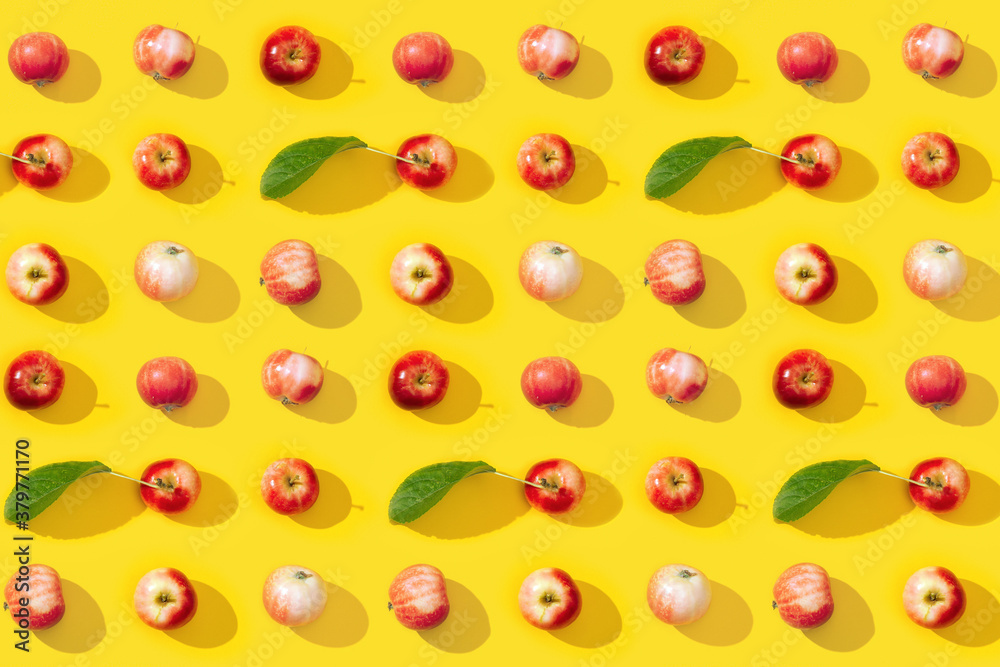 Regular creative pattern from small red apples and green leaves with dark shadows. Regular creative pattern from small red apples and green leaves with dark shadows.